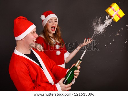 Happy traditional Santa Claus and mrs. Santa opens the champagne
