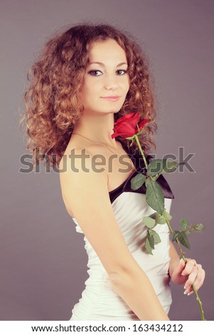 beautiful girl with curly hair and a red rose flower. studio photo shoot
