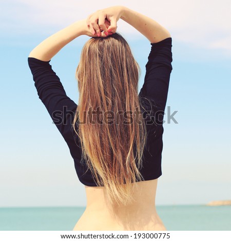 Girl with a beautiful figure stands with his back to the camera. Silhouette of a female figure on the beach background. Photo toned style instagram filters