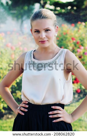 Outdoor portrait of beautiful stylish young woman wearing black skirt and beige silk blouse. Photo toned style instagram filters