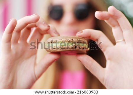 Hipster girl in a cafe eating macaroon.