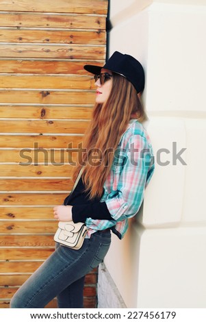 portrait of beautiful cool girl gesturing in hat and sunglasses over grunge wall