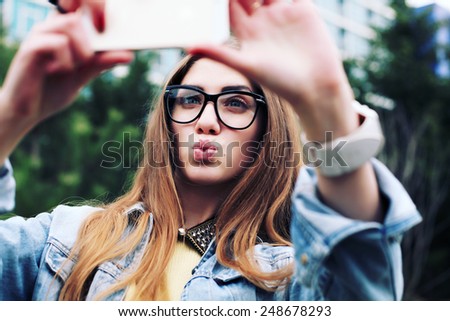 Pretty young female tourist makes selfie. Beautiful urban woman taking picture of herself. Filtered image.