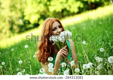 Image of pretty woman sitting on dandelions field, happy cheerful girl resting on dandelions meadow, relaxation outdoor in springtime, vacation