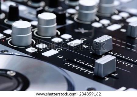 DJ mixer controller. Faders and switches of silver audio mixing console in nightclub. Selective focus.
