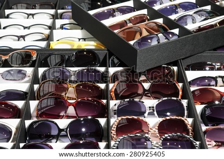 Many sunglasses, wide range of protective eyewear lying in the grey and white boxes, selective focus