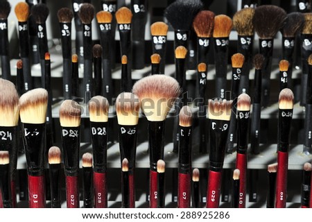 Many makeup brushes of black and red colors, with size indication of paintbrushes and with soft tips of different forms and colors, selective focus