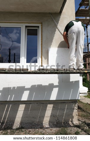 Worker placing styrofoam sheet insulation to the wall