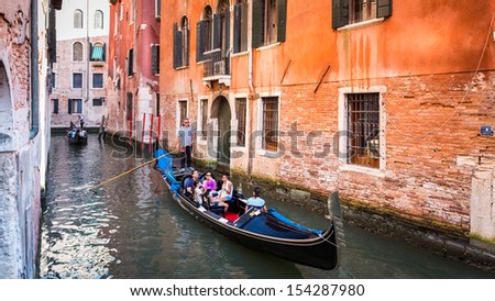 VENICE, ITALY - JULY 2013: Gondola with tourists sailing on a typical Venetian canal on July 26, 2013 in Venice Italy.