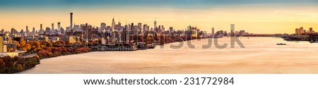 New York and Hudson River panorama as viewed from George Washington Bridge at sunset. Manhattan buildings reflect an orange glow from the last rays of the day.
