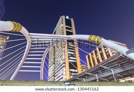 BANGKOK - Dec 27: Night view of high buildings and public sky walk for transit between Sky Transit and Bus Rapid Transit Systems at Sathorn-Narathiwas junction on Dec 27, 2012 in Bangkok, Thailand.