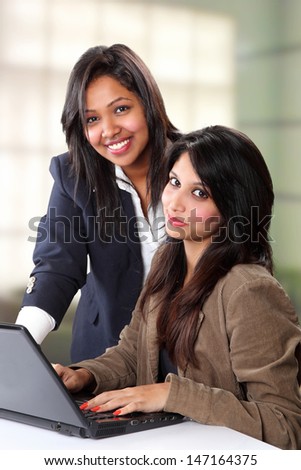 Smiling Indian business women  in front a laptop at office