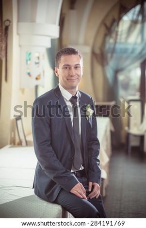 Cheerful groom sitting on the table one