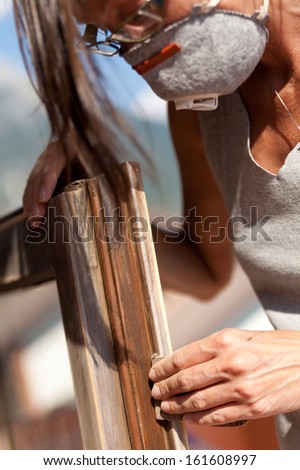 Do it yourself scene with a girl sanding a window under the sun in her terrace