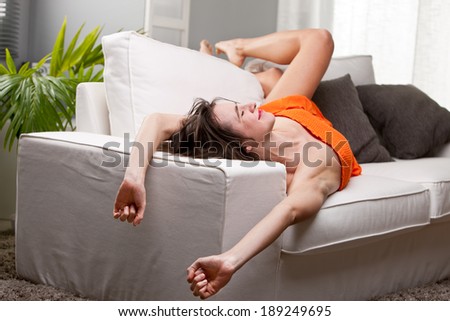 long legs girl yawning and stretching on her sofa while she wakes up