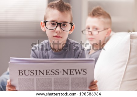 two little boys reading on newspapers or digital devices