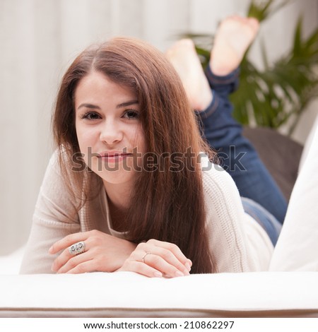 self confident beautiful young girl on a couch watching you and maybe a new idea she had