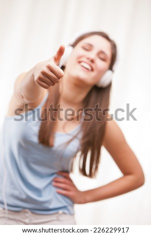 girl with thumbs up listening to music in her white headphones