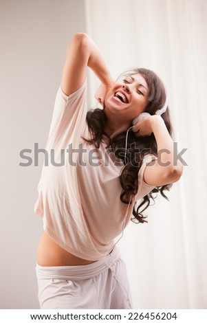 girl listening to music in her house dancing and singing happily in her living room