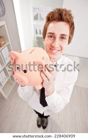 wide angle of a happy clerk with a piggy bank in his hands