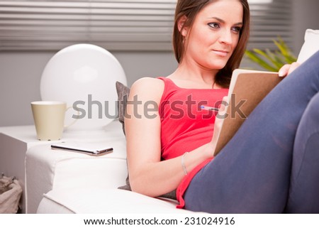 young beautiful woman studying on her couch because she knows that a serious education means MONEY