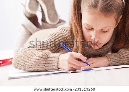 little girl drawing on her exercise book with a blue marker