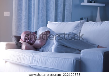 man sleeping on his couch in a white living room