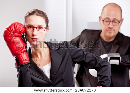 a business woman has been interrupted by a telephone call on her mobile while she was performing a box match with a business man that now is waiting for her to quit that call and keep on boxing
