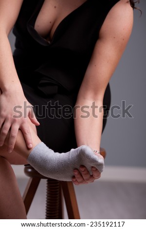 woman holding up her aching foot in a grey sock