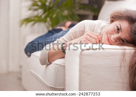 young pretty girl lying on a couch and smiling on her living room because her life is good
