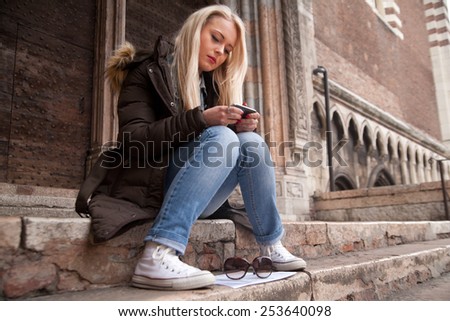 woman on stairs with a mobile phone sending text messages