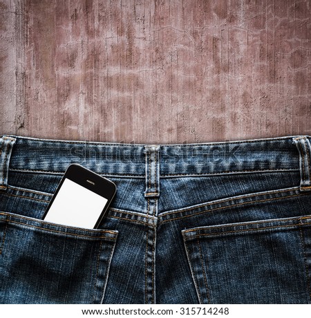 Blue jeans with cell phone in a pocket on vintage background