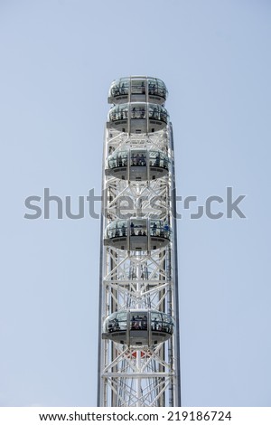 London, England - July 29th 2014: Tourists riding the London Eye. Side view of the London eye with people inside the pods. Each pod takes one hour to go round the eye, providing great views of London.