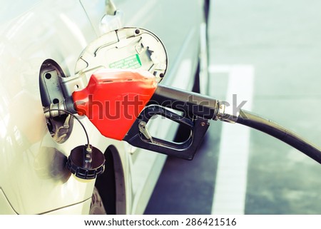 Red pumping fuel oil in car at gas station-retro