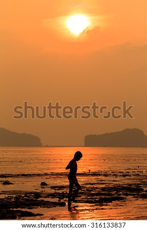 Silhouette of happy children walk on the beach when sunrise, Thailand