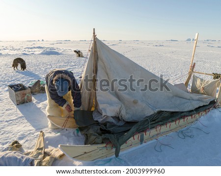 Inuit hunter wearing traditional trousers and boots made from polar bear fur is making his camp on the sea ice of the Melville Bay near Kullorsuaq in North Greenland.