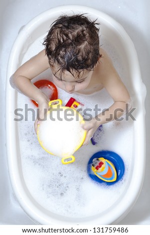 Toddler enjoying bathtime with soap foam / Funny bath time