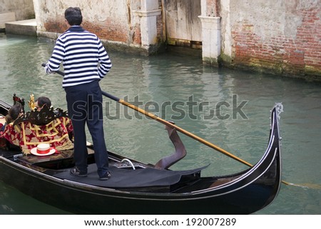 VENICE, ITALY - MAY 4, 2014: Unidentified Gondolier are boating tourists in the typical black gondolas along the canal in Venice