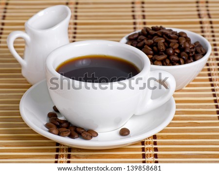 Coffee cup with saucer, bowl with coffee beans and milk jug