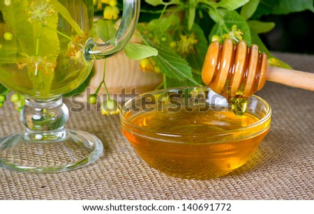 Bowl with linden honey and glass with linden tea on the table