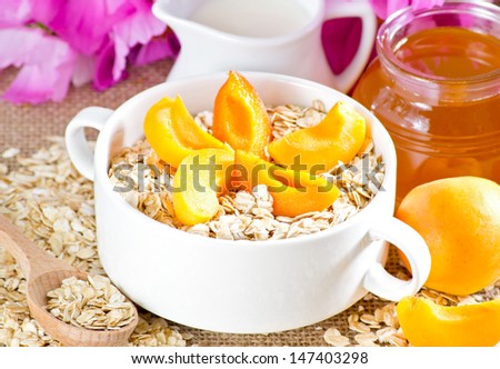Apricot  in the bowl, oatmeal, honey,  milk jug and flowers