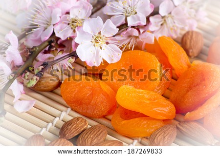 Dried apricots with almonds and blossoming branch on bamboo napkin. For this photo applied vignetting