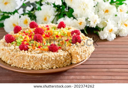 Cake with nuts, candied fruits and raspberries on  bamboo mat and flowers
