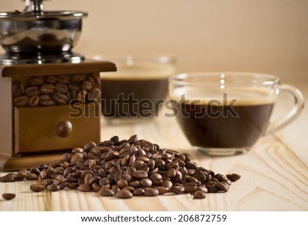 Coffee cup with coffee mill and coffee beans on the wooden table