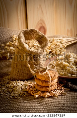 Oatmeal in the plate, oat flakes in the bag, oat cookies and spikelets on sackcloth
