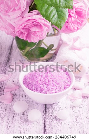 Spa salon with sea salt, towel, roses and rose petals on the wooden board.  For this photo applied color toning effect.