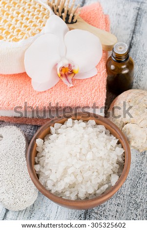 Spa salon with sea salt, towels and flowers on worn wooden boards