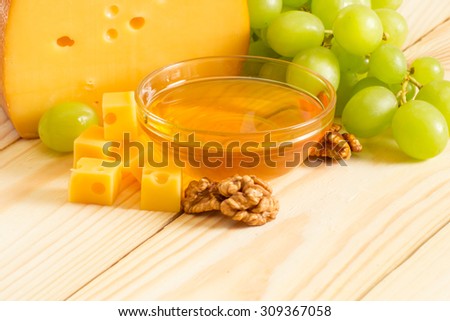 Smoked cheese, honey, walnuts and grapes on the wooden board