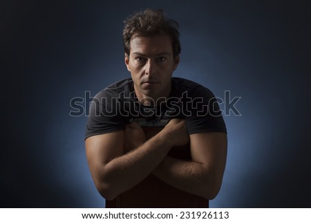 Portrait studio of cute man with crossed arms and sitting on a chair with black and blue background light