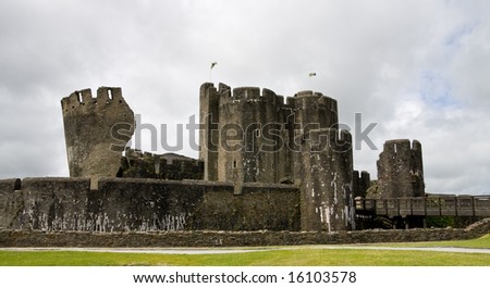 Towers of Caerphilly Castle with Welsh flags in South Wales, UK